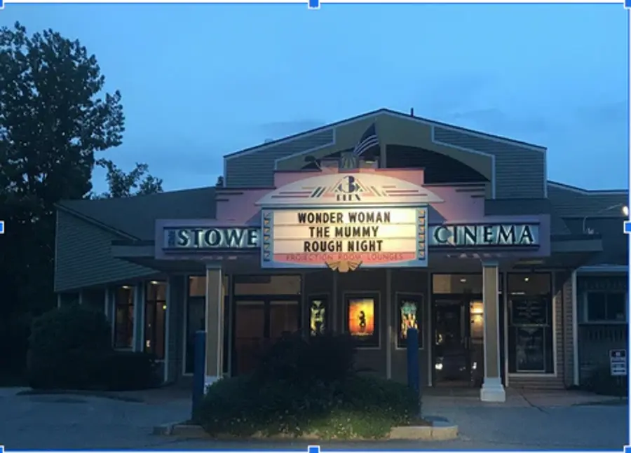 Cinema at dusk with marquee listing films: Wonder Woman, The Mummy, and Rough Night. Warm lights and a peaceful evening setting.