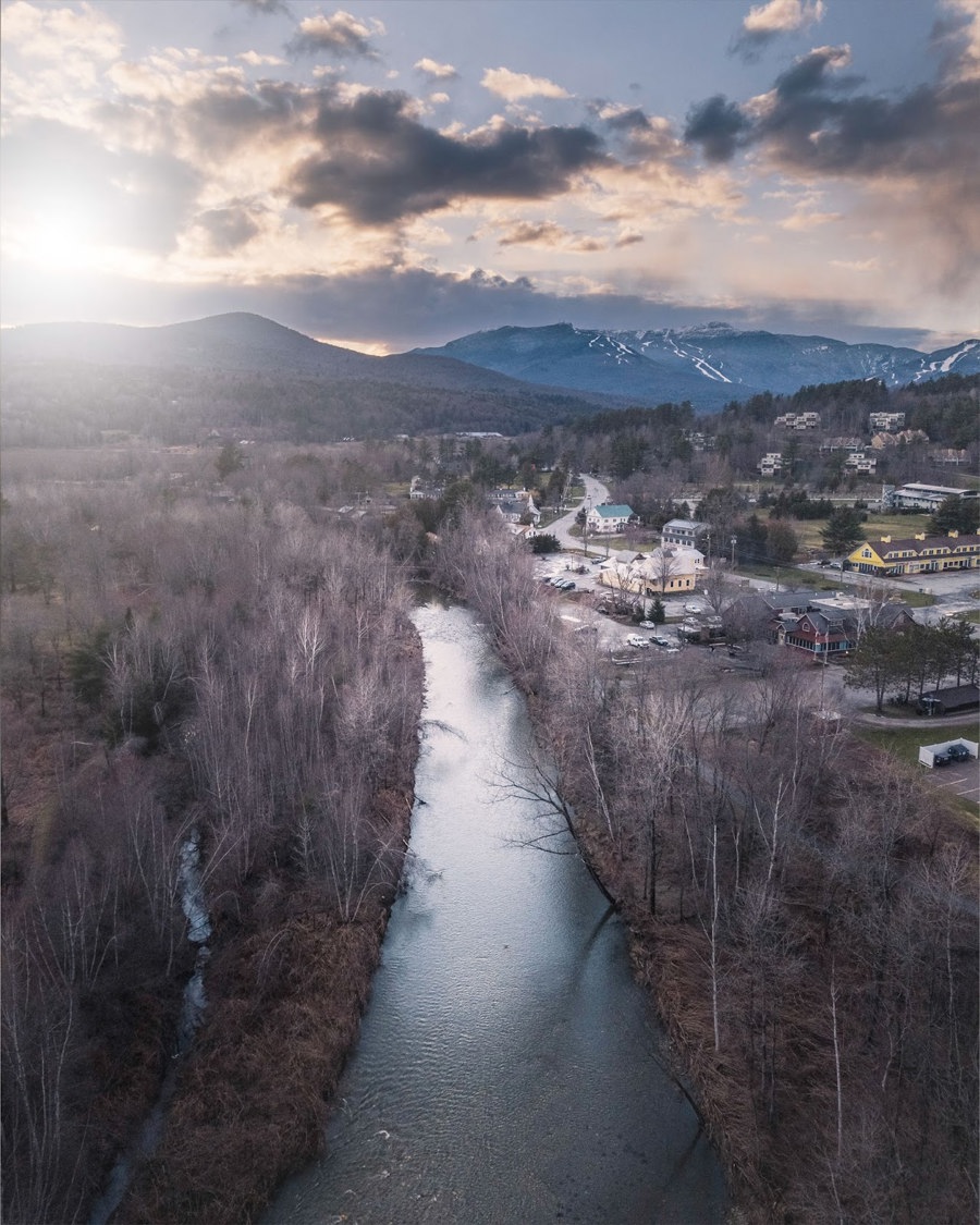 Aerial view showcasing a winding river surrounded by majestic mountains under a clear blue sky.