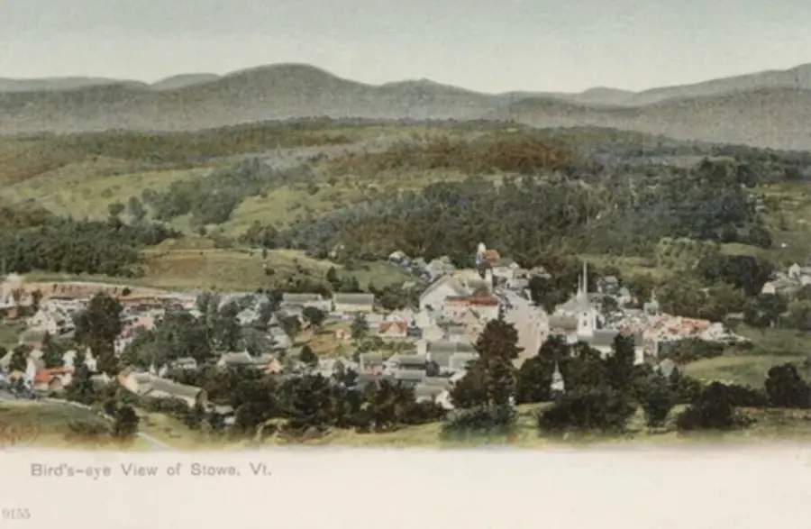 Bird’s-eye view of Stowe, Vermont, featuring a quaint town with clustered buildings and a prominent church steeple, set against rolling green hills.