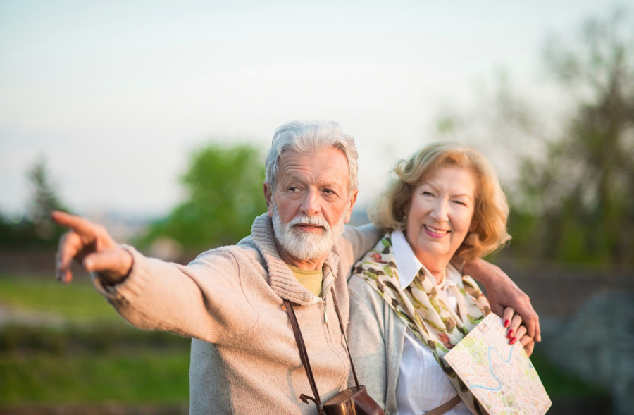An elderly couple gestures towards something off-screen, displaying interest and connection in their interaction.